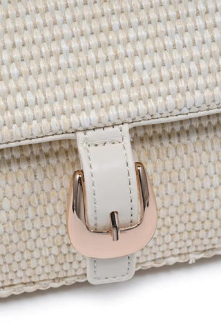 Close-up of a beige textured handbag with a gold buckle on a white background