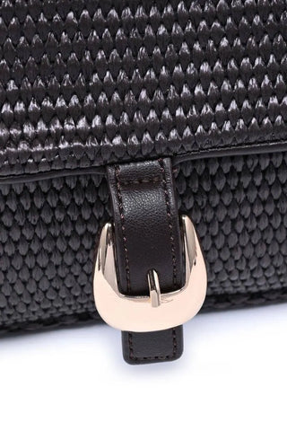 Close-up of a textured chocolate handbag with a gold buckle on a white background