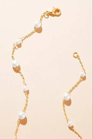 Gold bracelet with pearls on a beige background