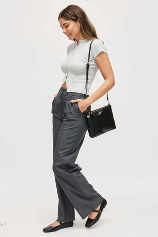Woman styling black croc texture crossbody bag with relaxed trousers and fitted knit top