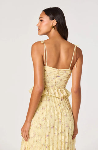 Woman wearing a yellow floral dress with thin straps on a white background