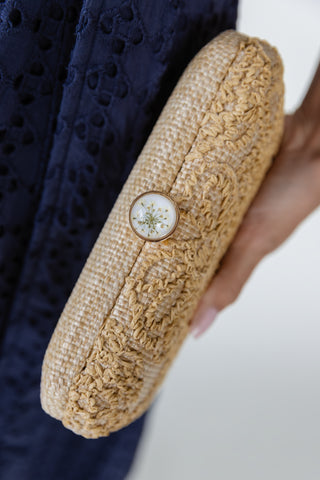 Close up of Carter evening clutch showing raised floral embroidery, woven textured body and polished gold-tone metal frame with jewel clasp
