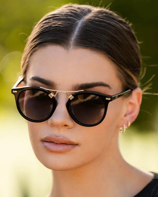 Woman wearing sunglasses with a blurred green background