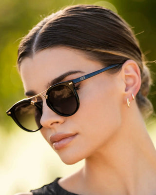 Woman wearing sunglasses with a blurred green background