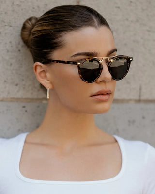 Woman wearing sunglasses with a neutral background