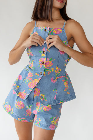 Close up of Jardin floral cotton denim vest showing delicate floral print, straight neckline with shoulder straps and button-front detail