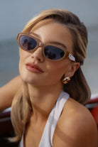 Woman wearing sunglasses and a white top by the water