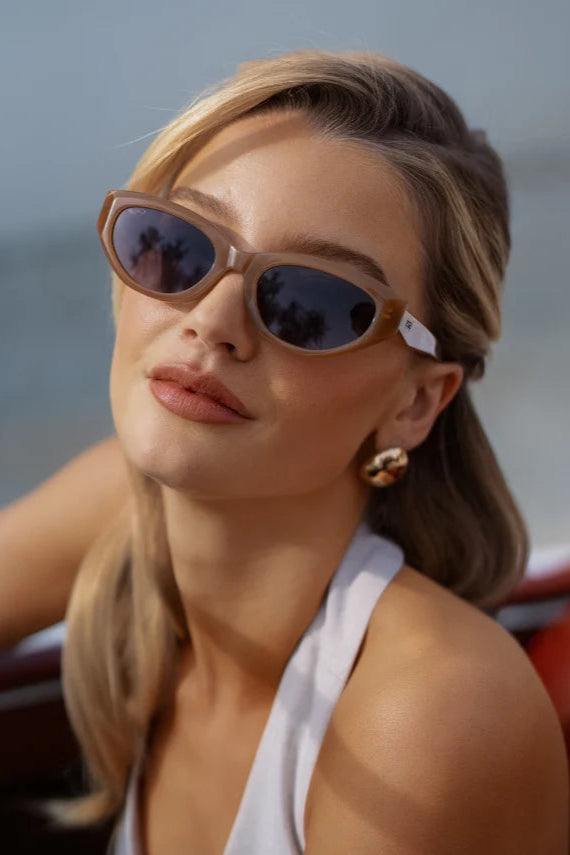 Woman wearing sunglasses and a white top by the water