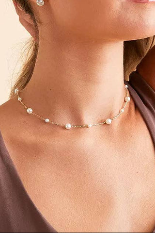 Woman wearing a pearl necklace and earrings against a beige background