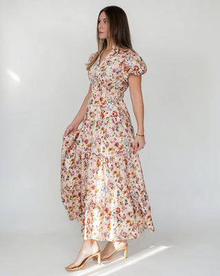 JO+CO Britton floral maxi dress in ecru with a tiered skirt, notched V-neck, and elasticized waist. Made of cotton.